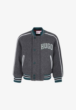 Graue Collegejacke mit grün-weiß gestreiften Bündchen, Kragen und Saum, mit weißen Paspeln und "HUGO" auf der Brust gestickt.