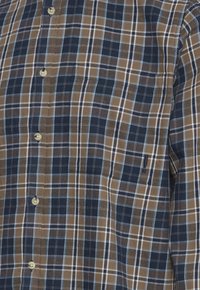 Langärmliges Hemd mit einem karierter Muster in Dunkelblau, Braun und Hellblau. Besteht aus weichem Stoff und hat eine Brusttasche.