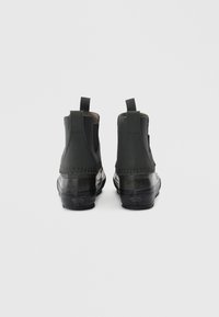 Botas negras hasta el tobillo con un empeine de cuero suave, paneles laterales elásticos y una suela de goma resistente. Incluyen lengüetas para ponerlas y quitarlas fácilmente.