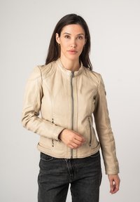 Beige leren motorjack met een staande kraag, ritssluiting aan de voorkant en twee zijzakken, met gestitchte details op de schouders.