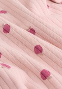 Rosa gerippter Stoff mit maulbeerfarbenen Punkten und kleinen beigen Schatten, die ein weiches, strukturiertes Muster erzeugen.