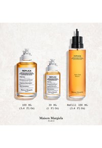 Trois flacons de parfum Maison Margiela Replica Jazz Club couleur ambre en tailles 100 ml, 30 ml et recharge de 100 ml sur un fond clair.