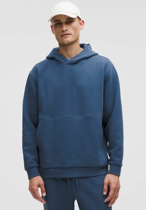 Blå bomulds hoodie med kænguruintropose, justerbar snor og ribbede manchetter, parret med matchende bukser. Enkel, afslappet design.