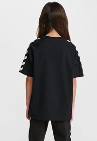 T-shirt in cotone nero a maniche corte, con dettagli a strisce argentate sulle spalle e un design a vestibilità rilassata.