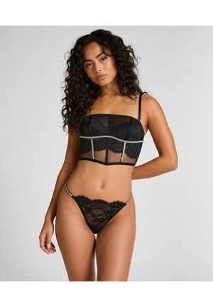 Schwarzes Spitzen-Nachtwäsche-Set mit einem Korsett-Design-Oberteil mit durchsichtigen Einsätzen und verstellbaren Trägern, kombiniert mit einem passenden Tanga mit Spitzenbesatz.