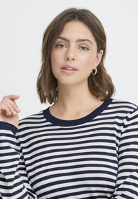 Pull rayé bleu marine et blanc avec un col rond et des manches longues. Le tissu semble doux avec une texture lisse et une coupe décontractée.