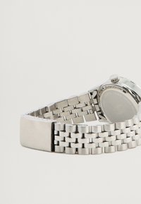 Sølv rustfrit stål armbåndsur med et metalled, der har et rundt urkasse og en struktureret krone, der viser vandtætheden på bagsiden.