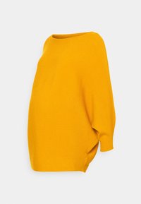 Pull ample en maille jaune moutarde avec large encolure bateau et longues manches chauve-souris sur fond blanc uni.