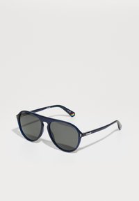 Ochelari de soare bleu marin cu lentile ovale, nuanță de gri închis și un cadru din plastic ușor. Prezintă o marcă discretă și un logo multicolor pe braț.