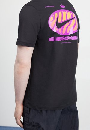 Schwarzes Baumwoll-T-Shirt mit einem auffälligen pinken und orangefarbenen Grafik auf dem Rücken, das das Nike-Logo und Text zeigt. Kurze Ärmel und eine lockere Passform.