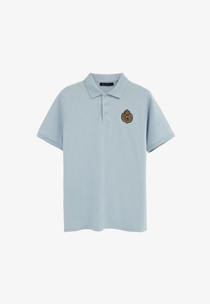 Hellblaues Poloshirt mit kurzen Ärmeln, drei Knöpfen und einem kleinen bestickten Wappen mit Krone und "P" auf der linken Brust.
