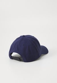 Casquette snapback bleu marine avec une texture de tissu solide, visière plate, design à six panneaux et sangle en plastique réglable à l'arrière.