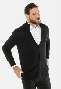 Schwarze Zip-Up-Cardigan aus einem strukturierten Strickmaterial. Er verfügt über einen gerippten Kragen und Bündchen sowie ein Slim-Fit-Design.