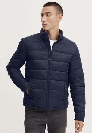 Navy puffer jacket with a zip front, horizontal quilted design, high collar, and side pockets, made from a lightweight, smooth material.