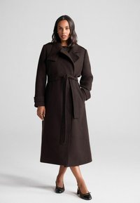 Trench coat in lana marrone con colletto ampio, vita regolabile da una cintura e maniche lunghe. Tessuto liscio e design fino al ginocchio con tasche laterali.