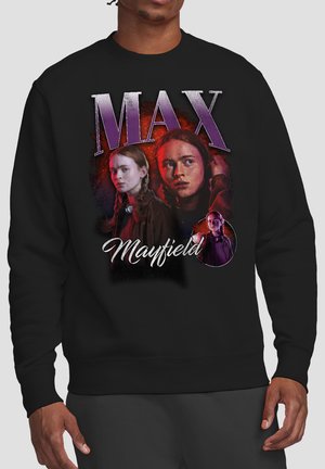 Schwarzer Pullover mit drei Porträts eines Mädchens mit geflochtenen Haaren, darüber in großen Buchstaben "MAX" und darunter "Mayfield".