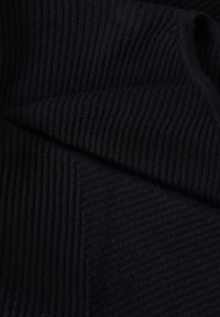 Tissu tricoté noir à côtes, plié pour montrer la texture et les détails du matériau doux et confortable.