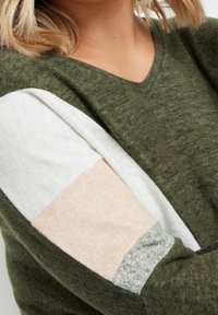 Pull à col en V vert olive avec des détails color-block en blanc, rose et gris sur les manches ; tissu texturé avec une apparence douce et chaude.