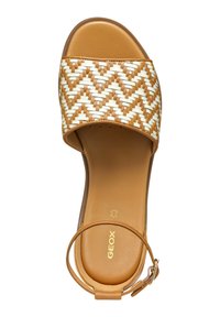 Sandal con correa de trenzado marrón, con una plantilla suave color bronce y hebilla en el tobillo. Presenta un patrón geométrico en la correa. Logo de la marca en la plantilla.
