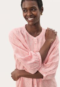 Red and white striped button-up shirt with a round collar and long, slightly puffed sleeves. Lightweight fabric with a soft texture.