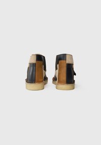 Brown and black leather ankle boots with patchwork design, featuring a textured surface and a light tan rubber sole.