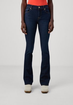 Jean évasé bleu foncé en denim, doté de poches avant et d'un système de fermeture à boutons, avec des coutures contrastantes discrètes et une texture lisse.