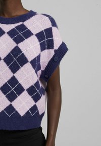 Stickad tröja med ett lila och rosa argyle-mönster, korta ärmar med marinblå ribbade manschetter och knapppaneler vid ärmarna.