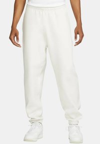 Weiße Jogginghose mit elastischem Bund, eng anliegenden Bündchen und Seitentaschen. Hergestellt aus einem weichen Stoff mit glatter Textur.