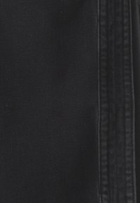 Tessuto in denim nero con una texture liscia, caratterizzato da una cucitura visibile e una leggera lucentezza, che conferisce un aspetto strutturato.