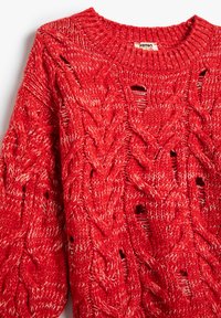 Suéter de punto rojo con un patrón de cable texturizado, que presenta puntos abiertos y un cuello acanalado. Fabricado con una suave mezcla de algodón.