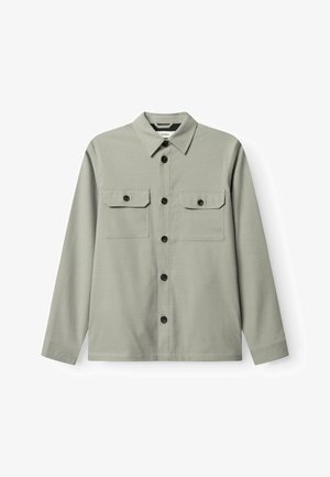 Chemise boutonnée vert clair à manches longues, deux poches poitrine et boutons marron foncé. Tissu lisse avec une texture unie.
