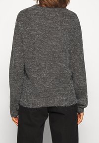 Pullover grigio lavorato a maglia con colletto rotondo, maniche lunghe e finitura testurizzata. Vestibilità rilassata con orlo e polsini a costine, e design casual.