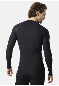 Zwarte sporttop met lange mouwen, ribbelstructuur, mesh inzetten op de schouders en een strak ontwerp. Glad materiaal, geschikt voor het sporten.