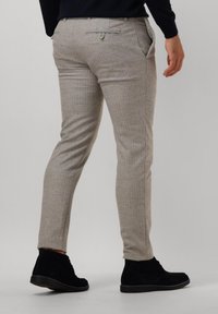 Light gray trousers with a subtle check pattern, slim fit, and side pockets. Features a button detail on the back pocket and worn with black shoes.