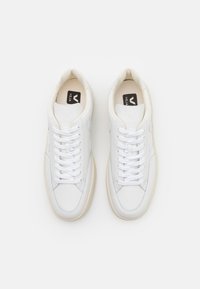 Hvite lær sneakers med en glatt finish, med rund tå, hvite snørebånd og en kremfarget gummi såle. Svart logo på innersålen.