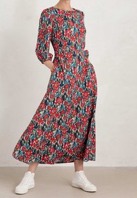 Robe maxi à imprimé floral rouge avec des manches trois-quarts, des poches et un col rond, associée à des baskets montantes blanches.