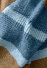 Écharpe en laine avec des rayures horizontales en bleu clair, bleu foncé et marron. Texture douce avec un mélange de motifs côtelés et lisses.
