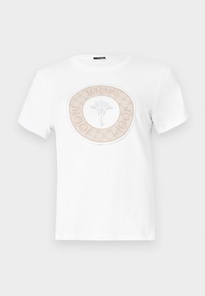 Vit bomullströja med en cirkulär beige logotypdesign med ett blommönster i centrum och text runt kanten.