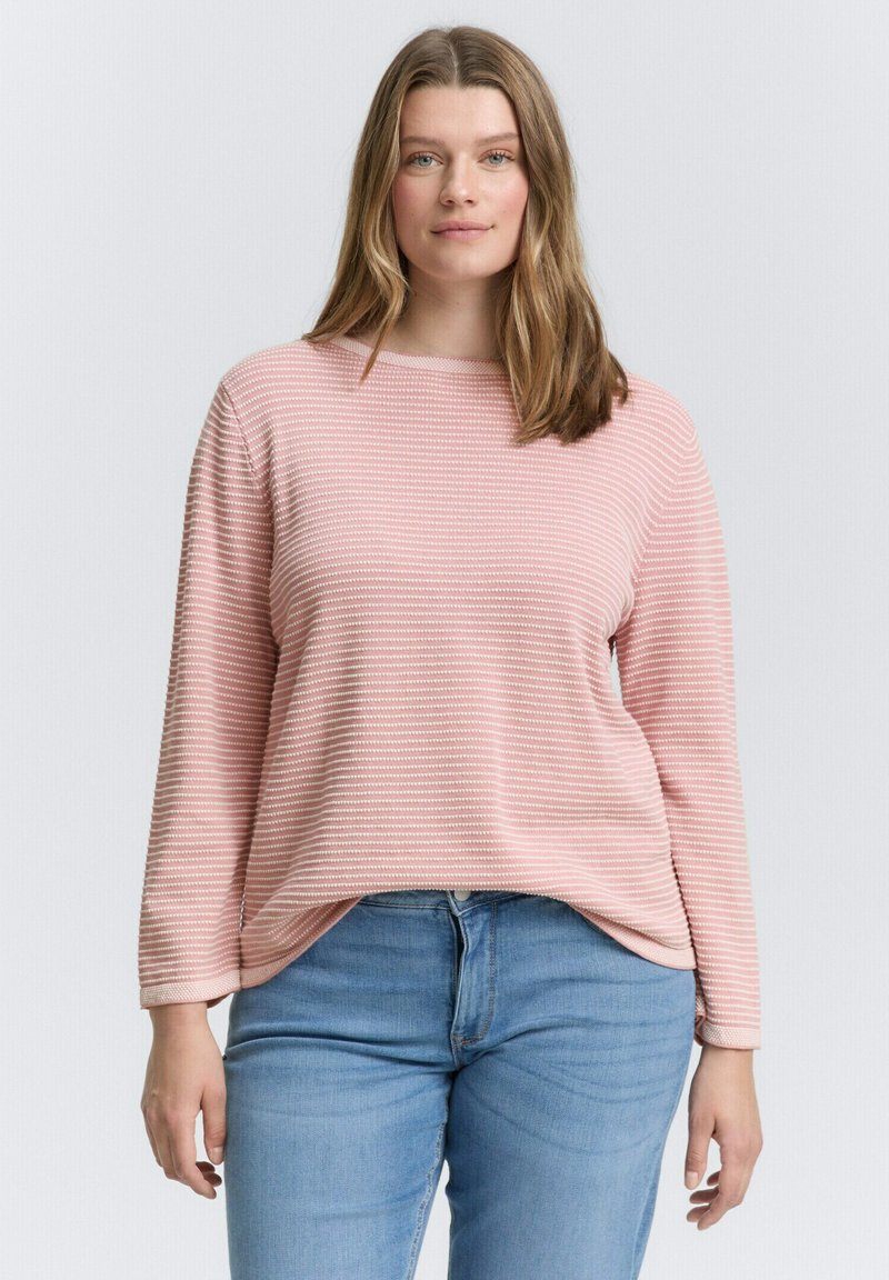 Rosa Langarmshirt mit geripptem Textil und horizontalen Streifen, kombiniert mit hellblauen Jeans. Das Shirt hat einen entspannten, lockeren Schnitt.