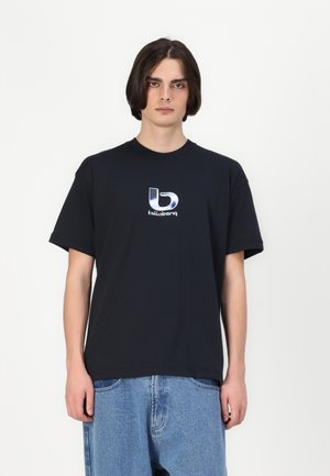 Black cotton t-shirt with a round neckline, short sleeves, and a reflective logo on the chest. Paired with light blue loose-fit denim shorts.
