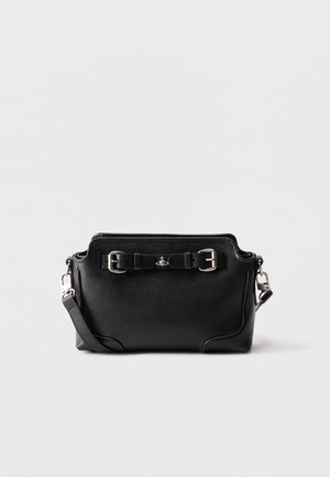 Sac bandoulière en cuir noir avec boucles en argent, une sangle détachable et un petit emblème argenté sur un fond uni.