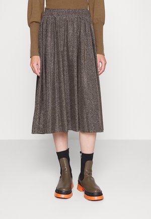 Jupe midi marron métallisée avec taille élastique, associée à des bottines kaki avec tissu noir et semelles orange.
