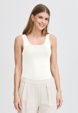 Weißes, eng anliegendes Tanktop mit Rundhalsausschnitt und breiten Trägern, aus glattem Stoff. Kombiniert mit hellbeigen, plissierten Hosen.