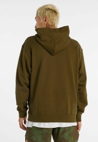 Felpa con cappuccio verde oliva dalla vestibilità comoda, con polsini e orlo costinati, realizzata in tessuto morbido, con cucitura posteriore e texture delicata.