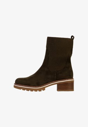 Stivaletto in suede marrone con tomaia in tessuto a coste, tacco a blocco e cuciture bianche a contrasto lungo la suola. Dettaglio della superficie testurizzata visibile.