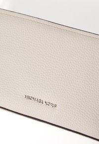 Helehall nahast rahakott tekstuuriga pinnaga. Omab hõbedast "MICHAEL KORS" logo ja kontrastset tumedat äärestust.