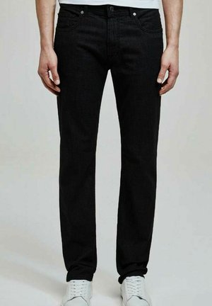 Jean en denim noir avec une coupe droite, design à cinq poches, fermeture à bouton et accents de baskets blanches. Texture lisse, design classique.