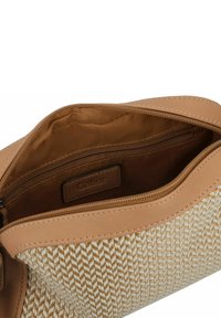 Sac en cuir tan avec un textile beige à motif tissé. Comprend une fermeture éclair et une poche intérieure. Intérieur doublé.