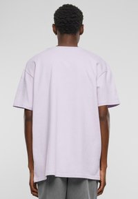 Lyse lilla oversized t-shirt med kortærmer, rund hals og en glat stoftekstur. Kanten er lige og let buet i siderne.