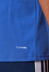 Blue athletic shirt with a textured finish. Features a "CLIMACOOL" logo in white near the hem. Accompanied by navy shorts with light stripes.